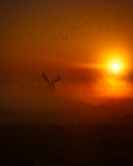 little windmill at sunrise with fog