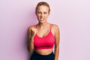 Fototapeta na wymiar Beautiful caucasian woman wearing sportswear angry and mad raising fist frustrated and furious while shouting with anger. rage and aggressive concept.