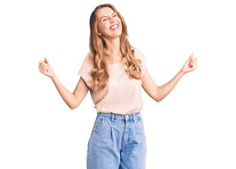 Young beautiful caucasian woman with blond hair wearing casual clothes very happy and excited doing winner gesture with arms raised, smiling and screaming for success. celebration concept.