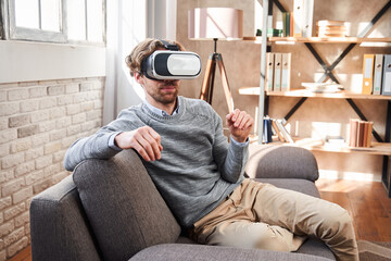 Fototapeta premium Man sitting at the cozy living room and using vr googles