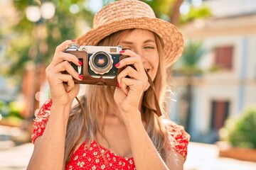 Young blonde tourist woman wearing summer style using vintage camera at the park