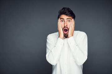 Shocked young man isolated against dark background