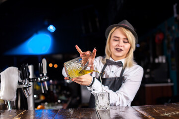 Girl barman makes a cocktail in the saloon