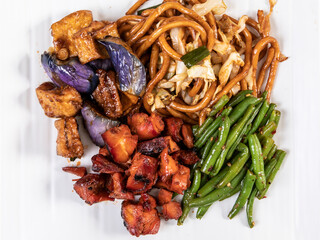 A plate of Chinese food with Chinese eggplant with tofu, beans, chicken and noodles