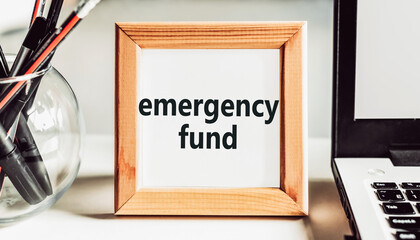 "Emergency fund" text in a wooden frame on an office table. Financial concept.