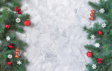 Christmas gray grunge background, fir twigs, berries, snowflakes and baubles, top view. New Year decoration, pine tree branches, cones vertical both sides on light concrete rough texture, copy space.