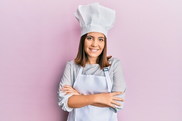 Young blonde woman wearing professional cook uniform and hat shouting with crazy expression doing rock symbol with hands up. music star. heavy concept.