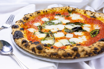 A view of a Margherita pizza pie, in a restaurant or kitchen setting.