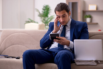 Fototapeta premium Young male employee working from home in pandemic concept
