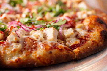 A closeup view of the chicken toppings and crust of a BBQ chicken pizza.