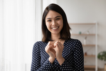 Head shot portrait close up smiling Asian woman showing heart gesture, expressing love, support and care, regular medical checkup promotion, cardiovascular diseases prevention, charity concept