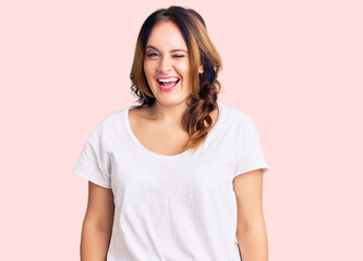 Fototapeta premium Young beautiful caucasian woman wearing casual white tshirt winking looking at the camera with sexy expression, cheerful and happy face.