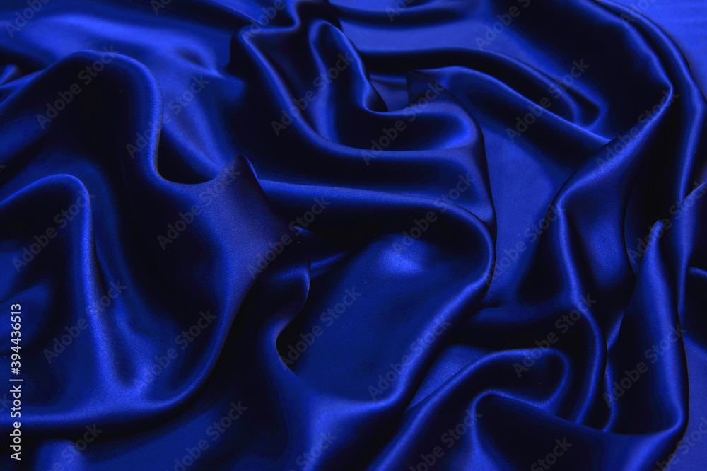 Wall mural dark blue silk wavy fabric background, view from above. smooth elegant blue silk or satin luxury clo