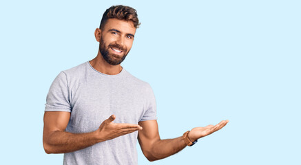 Young hispanic man wearing casual clothes inviting to enter smiling natural with open hand