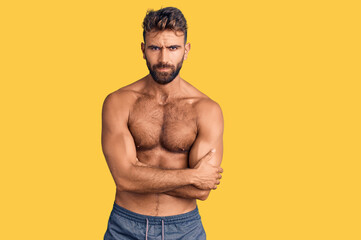 Fototapeta premium Young hispanic man wearing swimwear shirtless skeptic and nervous, disapproving expression on face with crossed arms. negative person.
