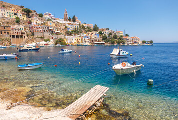 Fototapeta premium Simi-Greece-July 04, 2011: View of the Bay, beautiful colorful houses and fishing boats of Simi island, Greece