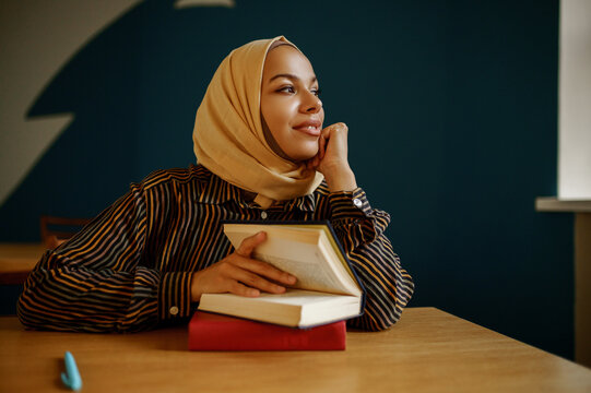Arab female student in hijab holds textbook