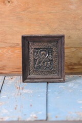 religious image of metal in a frame on a wooden background