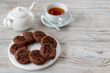 Chocolate chip cookies and a cup of tea on a wooden background.