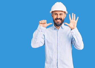 Young handsome man wearing architect hardhat showing and pointing up with fingers number six while smiling confident and happy.