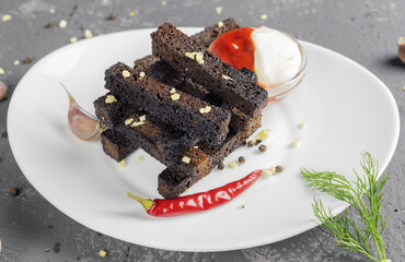 rye crunchy croutons or snacks in white plate on gray concrete background