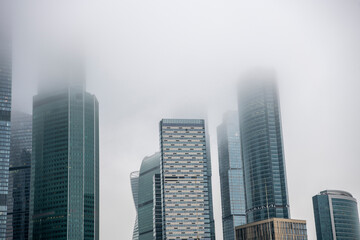 Fototapeta na wymiar cityscape with high-rise buildings whose upper floors have melted into fog