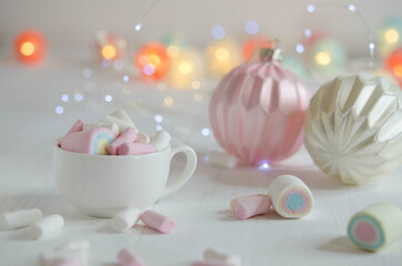 Cup with marshmallows and Christmas balls on a blurred background.