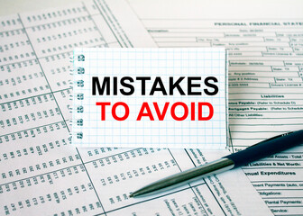Obraz premium Notepad with text Mistakes To Avoid lying on financial tables with a pen