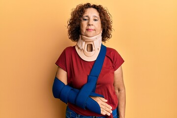 Beautiful middle age mature woman wearing cervical collar and arm on sling thinking attitude and sober expression looking self confident