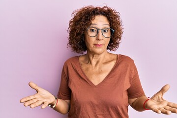 Beautiful middle age mature woman wearing casual clothes and glasses clueless and confused...