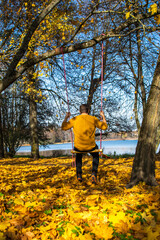 Fototapeta premium Photo of a young blonde woman on a swing in the middle of the woods in an autumn day. Vilnius.