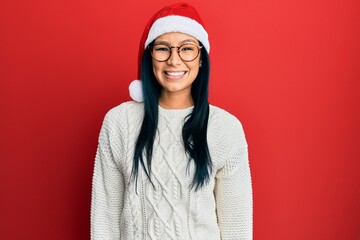 Beautiful hispanic woman wearing christmas hat with a happy and cool smile on face. lucky person.