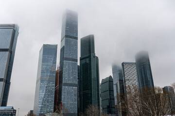 Fototapeta na wymiar cityscape with high-rise buildings whose upper floors have melted into fog