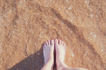 Relax on the ocean beach, female feet on the sea sand. Summer vacation concept