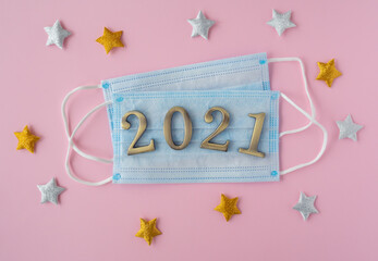 Christmas 2021. Coronavirus new year minimal concept. Flat lay with face masks, metal numbers and decorative stars on pink background. top view, copy space