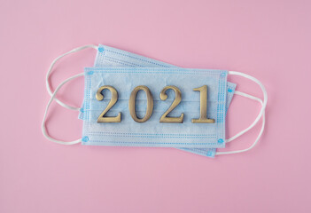 Christmas 2021. Coronavirus new year minimal concept. Flat lay with face masks, metal numbers on pink background. top view, copy space