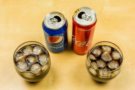 Niedomice, Poland - March 09, 2018: The cans of carbonated drink Pepsi and Coca-Cola were poured into glasses with ice cubes.