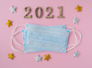 Christmas 2021. Coronavirus new year minimal concept. Flat lay with face masks, metal numbers and decorative stars on pink background. top view, copy space