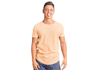 Fototapeta premium Young handsome man wearing casual clothes sticking tongue out happy with funny expression. emotion concept.