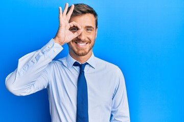 Handsome caucasian man wearing business shirt and tie smiling happy doing ok sign with hand on eye looking through fingers