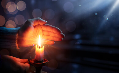 Defocused Hope Concept - Hands Holding Candle With Shining Flame And Blurry Lights