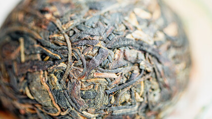 Chinese Raw Pu Er tea in the form of a nest in a paper wrapper, macro picture. 