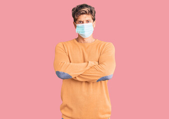 Young handsome man wearing medical mask skeptic and nervous, disapproving expression on face with crossed arms. negative person.