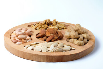 Mix of raw dried nuts on wooden plate isolated on white.
