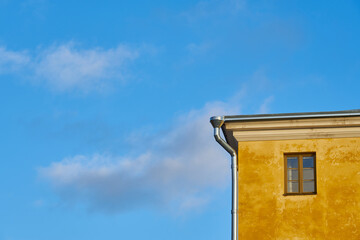 Fototapeta na wymiar Windows in a yellow house against the blue sky.
