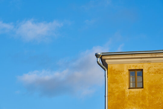 Windows in a yellow house against the blue sky.