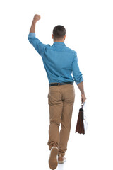 casual man celebrating succes while walking and holding a briefcase