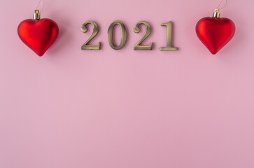 Christmas 2021. Coronavirus new year minimal concept. Flat lay with metal numbers and red hearts balls on pink background. Top view, copy space