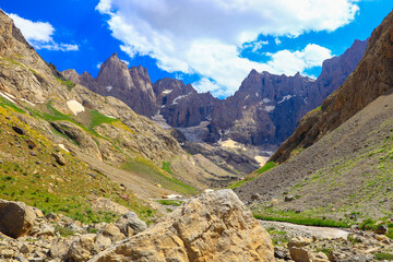 Fototapeta premium snowy mountains and blue sky, natural landscape, green meadows, white clouds, spring season and sunny day 