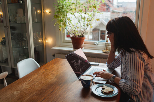 Woman with laptop in dining room, Sweden